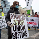 People hold placards during a protest in support of Amazon workers in Union Square, New York on February 20, 2021.